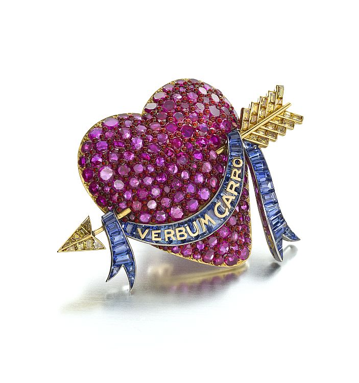 Millicent Rogers brooch by Paul Flato. Designed as a circular-cut ruby heart, interspersed with red enamel cabochons, pierced by an 18-karat gold arrow set with calibré-cut yellow diamonds, to the draped calibré-cut sapphire ribbon, mounted in platinum and 18-karat gold. Image: Siegelson. 