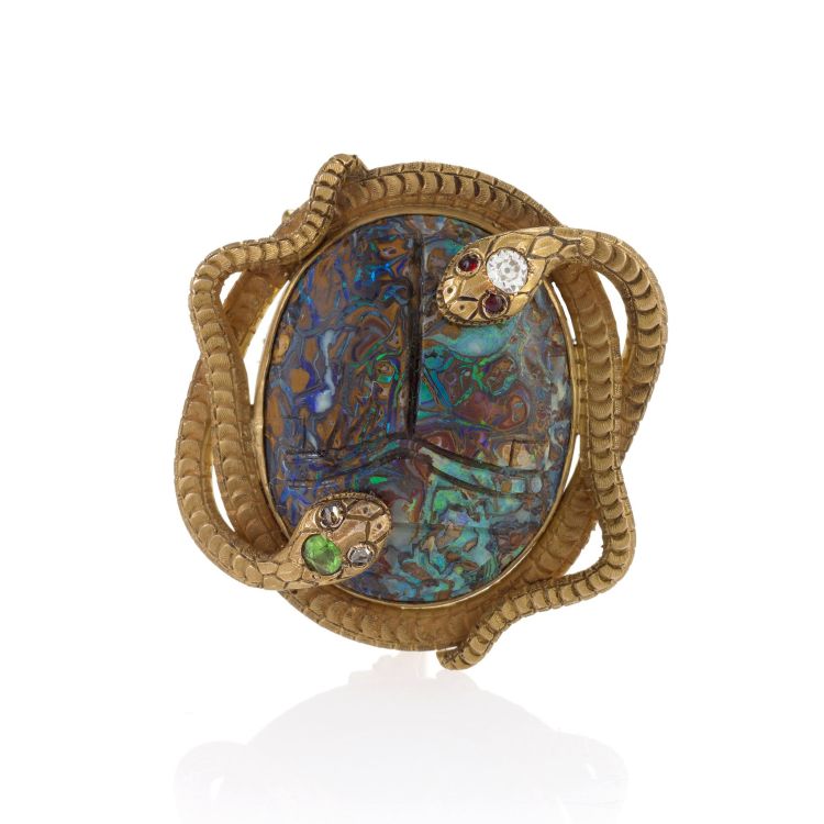 Egyptian Revival 18-karat gold pendant brooch, designed as a carved Yowah nut opal scarab framed by a pair of intertwined asps, one diamond eyes and demantoid garnet accent, the other with red garnet eyes and diamond accent, circa 1900. Photo: Macklowe Gallery. 
