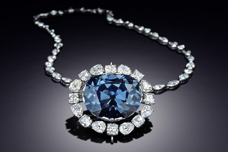 The 45.52-carat Hope Diamond is set in the platinum necklace designed by Cartier Inc. in 1911 when it was sold to Evalyn Walsh McLean. It is surrounded by sixteen approximately 1-carat brilliant-cut white diamonds and suspended from a chain with forty-six white diamonds. Image: Dane Penland, Smithsonian Institution, enhanced by SquareMoose Inc.