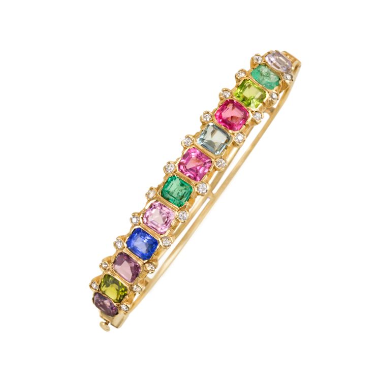 An antique gold half-hoop multicolored gem set bangle bracelet, featuring emeralds, pale amethyst, peridot, aquamarine, tourmalines, and sapphire, with diamond accents, in 14k. Kentshire