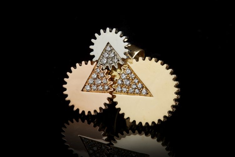 Meret Oppenheim Play kinetic ring in 18-karat white, yellow and rose gold, with three linked cog wheels, each with a diamond set with tiny diamonds that when re-aligned correctly create a large diamond, 1998. Photo: Didier. 