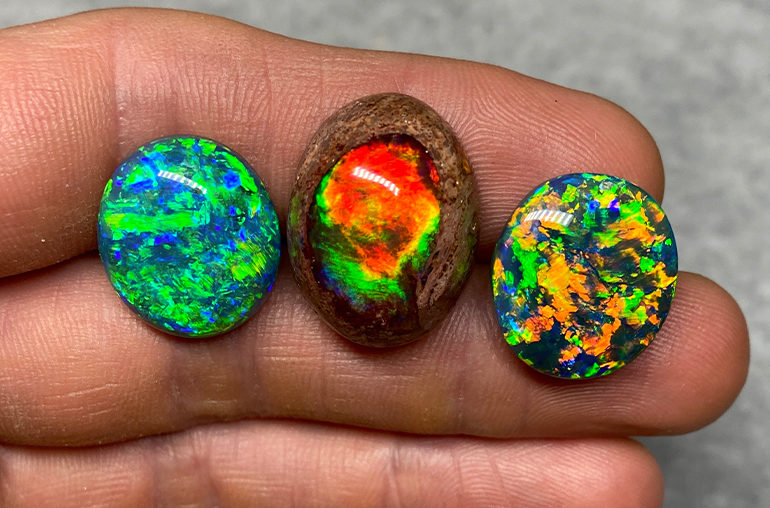 Two Australian black opals on either side of a beautiful Mexican opal. (Photo: Joel Price)