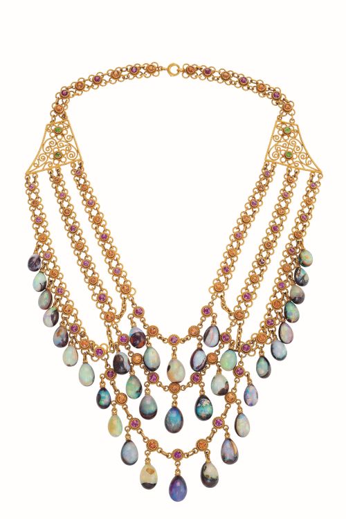 Three-tiered necklace comprised of three rows of alternating pink and orange garnets set in elaborately textured gold collets with delicate looping design elements, circa 1900-1910. From each tier of the necklace hang tear-shaped boulder opal beads. Photo: Anthony Virardi at Macklowe Gallery. 