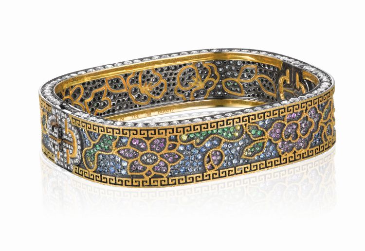 Yewn cloisonné flower bangle made up of pink, yellow and blue sapphires, tsavorite garnet, diamond, black rhodium-plated gold, yellow gold. The bangle is decorated with peach blossom, chrysanthemum, lotus flower and peony. (ACC Art Books) 